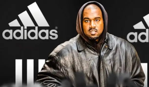 Kanye West wearing a black jacket in front of Adidas logos during the height of their partnership before their $1.2 billion separation